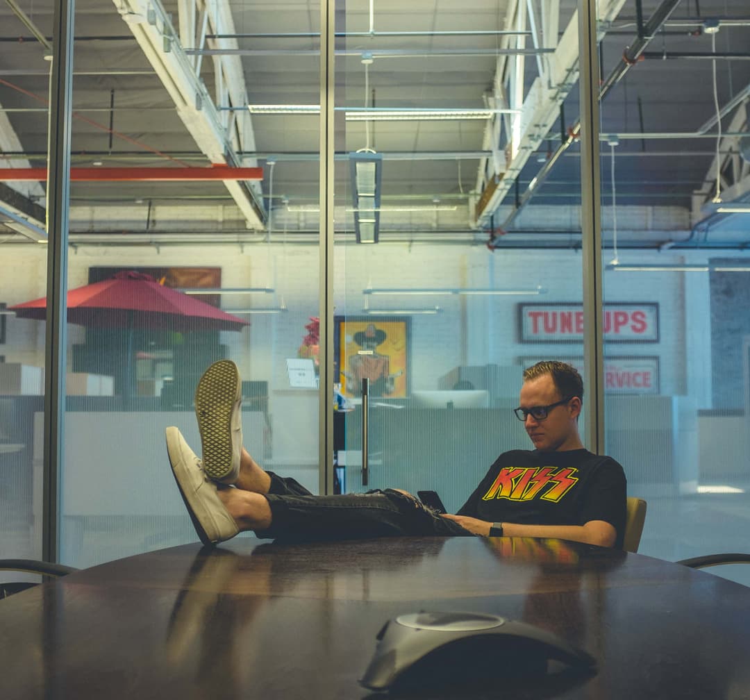 Man sitting beside table wearing black KISS printed T-shirt photograph