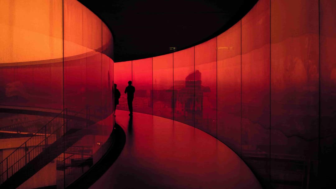 Man walking inside a red tinted glass building