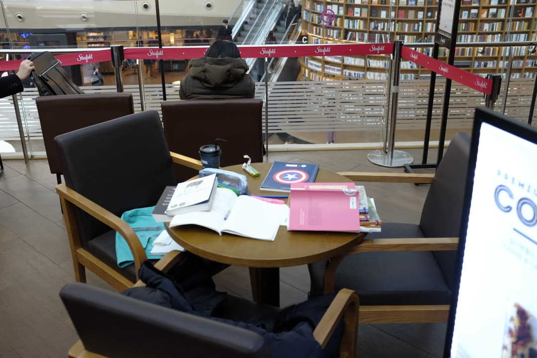 Photo of unoccupied table in a library covered in books