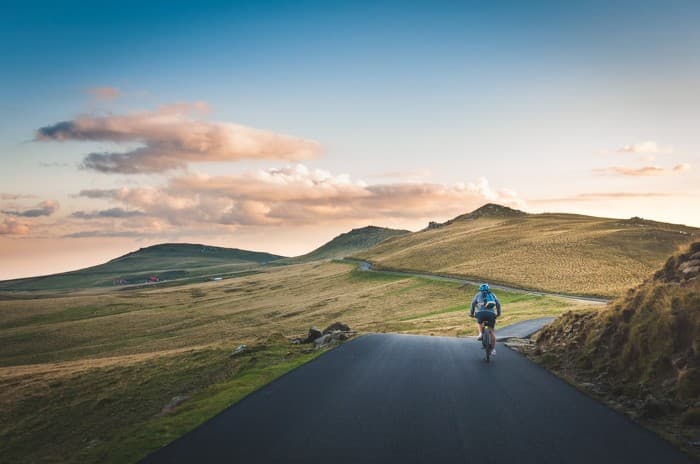 Landscape photograph of a solo cyclist on a mountain road