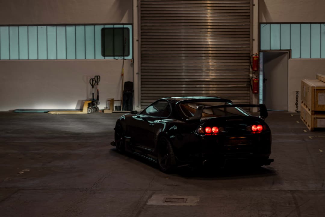 Landscape photo of a black Toyota Supra (Mark 4) from the back