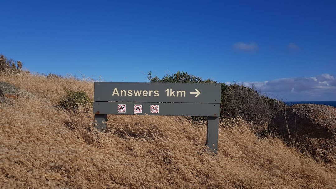A directional signpost on a trail path labelled as 'Answers 1km' with an arrow pointing off screen to the right