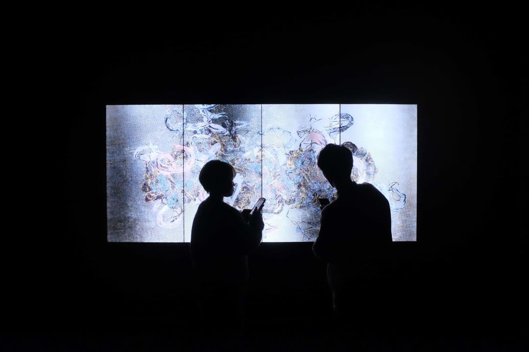Man and woman standing in front of a backlit artwork
