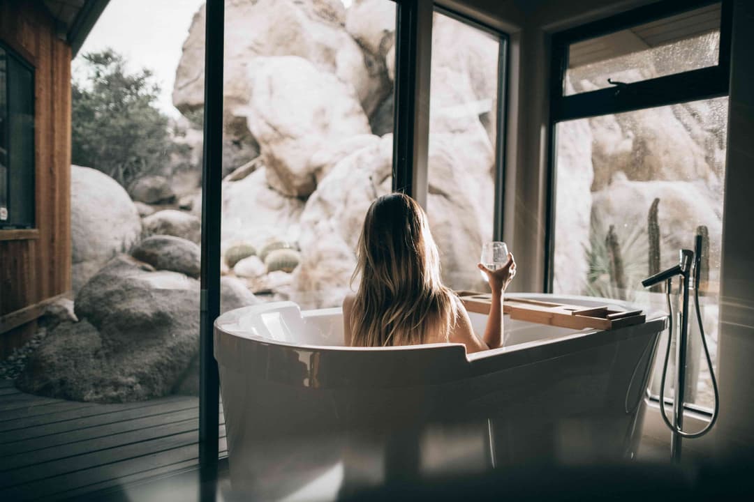 Woman holding a wine glass while sitting in a baththub